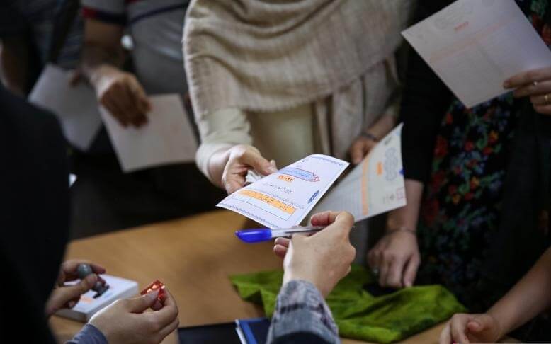 Voters receive ballot papers during the presidential election in a Jewish and Christian district in the centre of Tehran, Iran, May 19, 2017. TIMA/via REUTERS